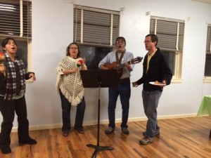 Viviana Susa Parra, Gloria Piper, Denys Vigil, & Rick Clifford lead DJPC in singing at the 2014 Holiday Party